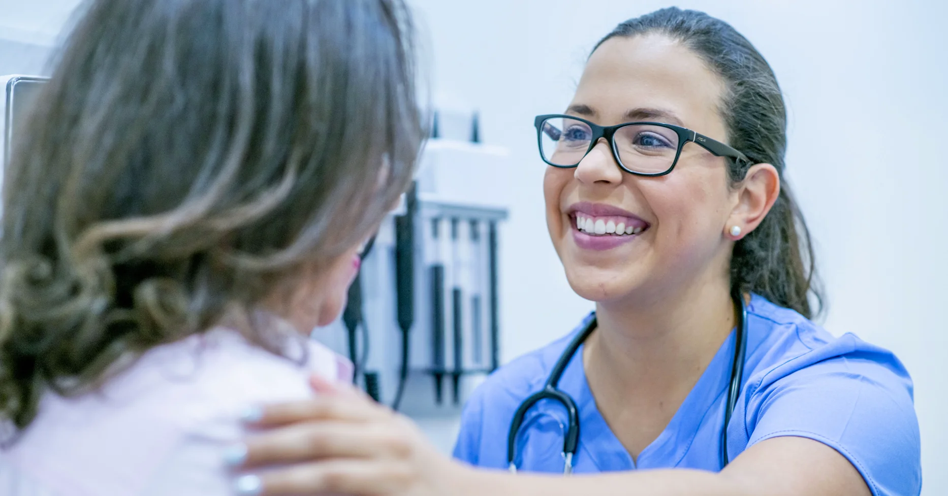 Close up of smiling nurse with hand on patient's shoulder in her office